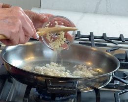 Minced garlic being added to shallots in the pan