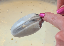 A finger drawn across the back of a spoon leaves a clean line in reduced cream sauce