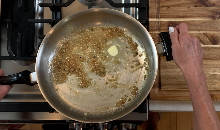 Cold butter being swirled into the pan sauce until glossy