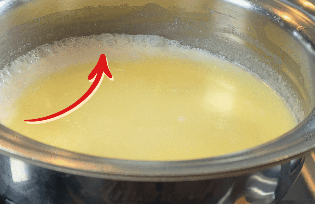 Tiny bubbles forming around the edge of a saucepan as cream reduces gently