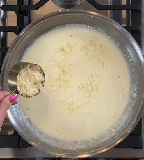 Sprinkling freshly grated parmesan gradually into a pan of reduced cream sauce