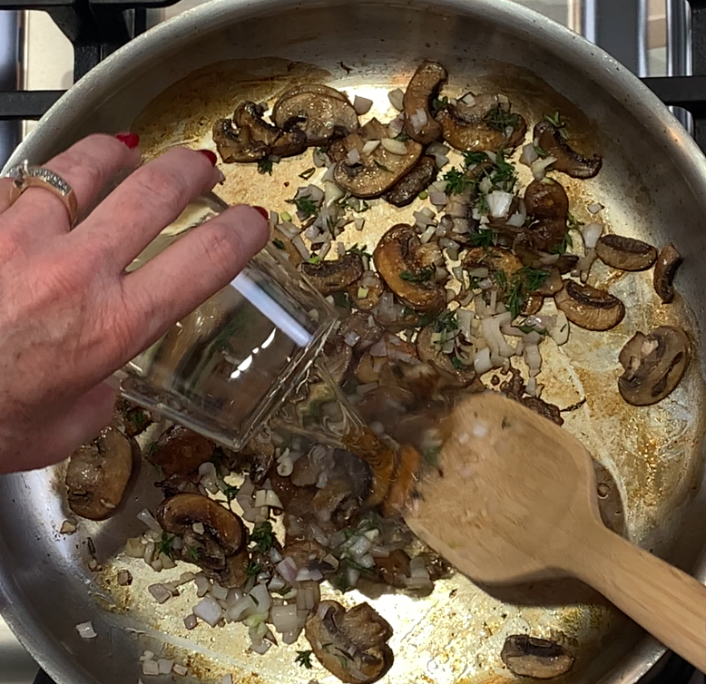 Pouring white wine into a hot pan with browned mushrooms, shallots and thyme to deglaze.