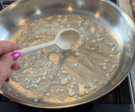 Minced garlic gently softening in melted butter over low heat in a stainless steel pan