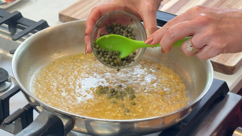 Adding rinsed capers to a lemon caper pan sauce