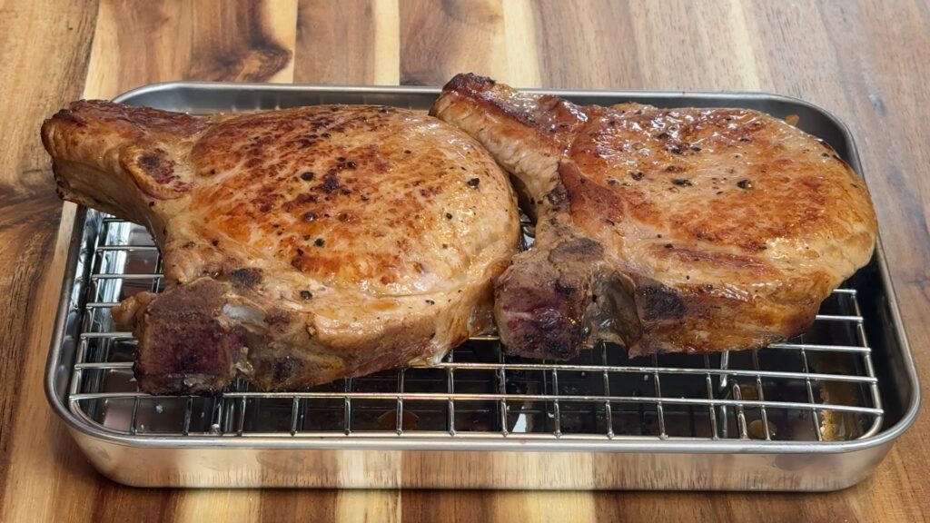 Seared pork chops resting on a wire rack