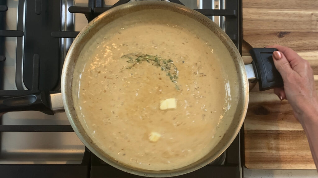 Finishing mustard cream pan sauce with thyme sprig and cold butter
