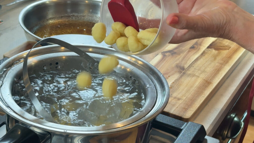 Adding gnocchi to pot of boiling water.