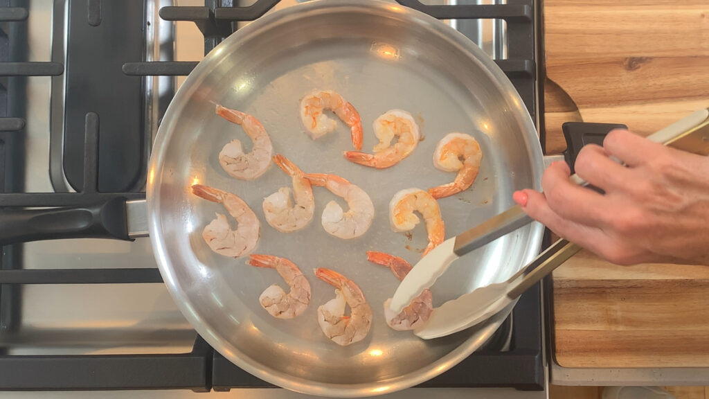 Shrimp searing in a hot pan, turning pink, flipping when ready