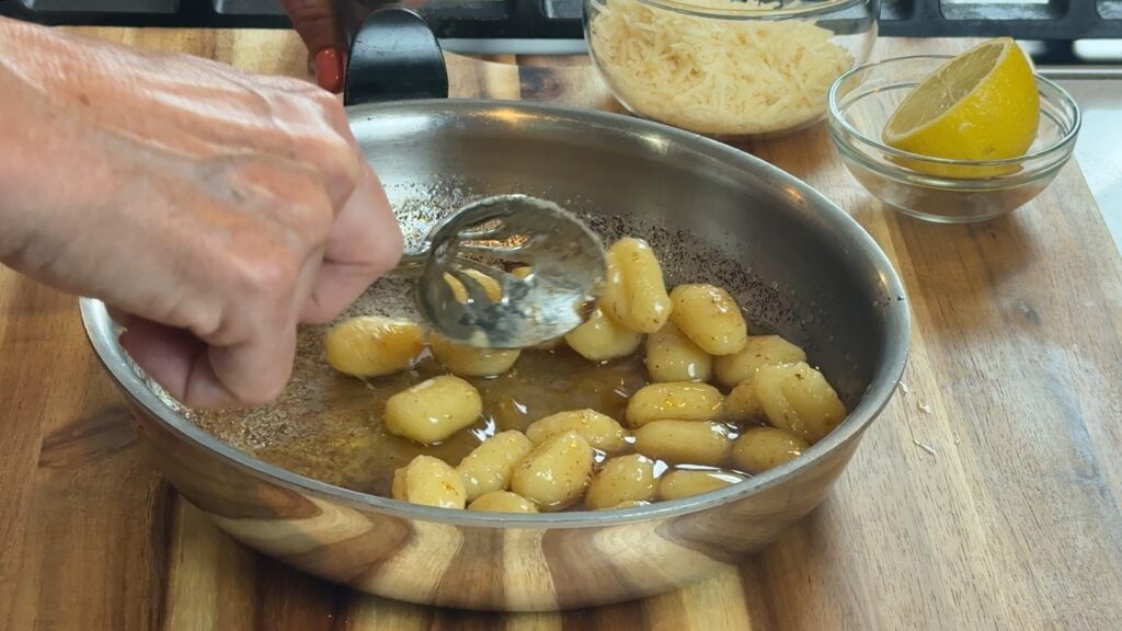 Tossing gnocchi in brown butter sauce off the heat. 