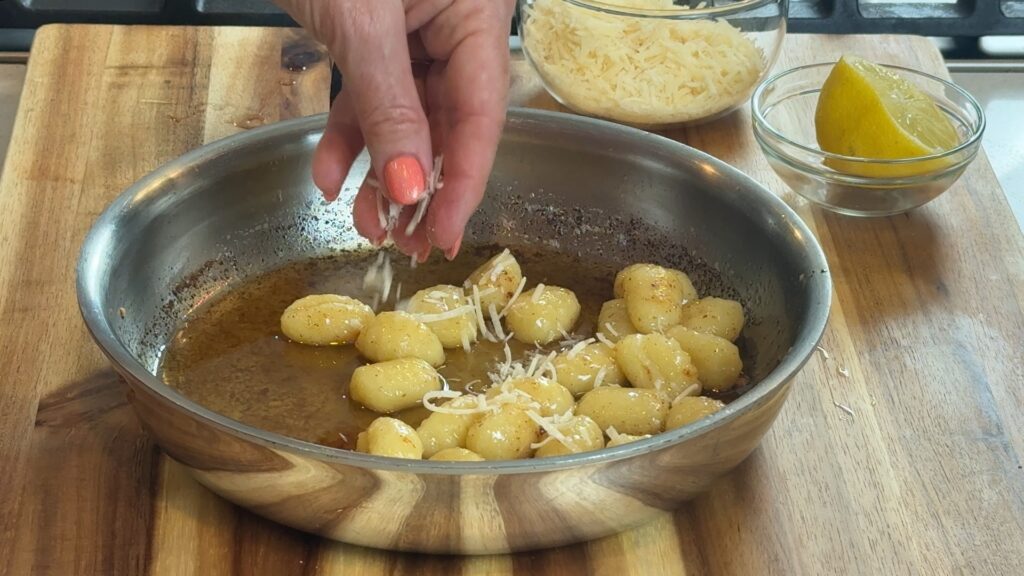 Finishing the gnocchi in a pan of brown butter sauce and adding parmesan cheese. 