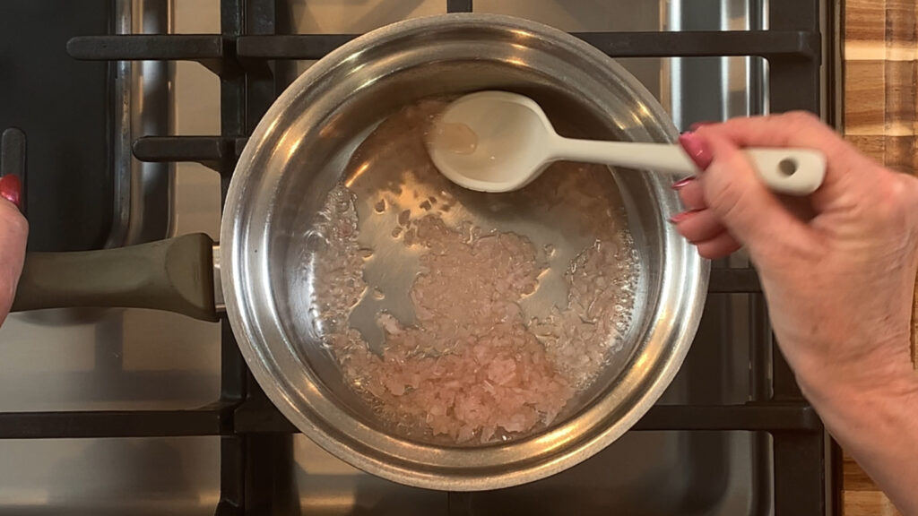 White wine, vinegar, and shallots reducing in a saucepan for beurre blanc sauce