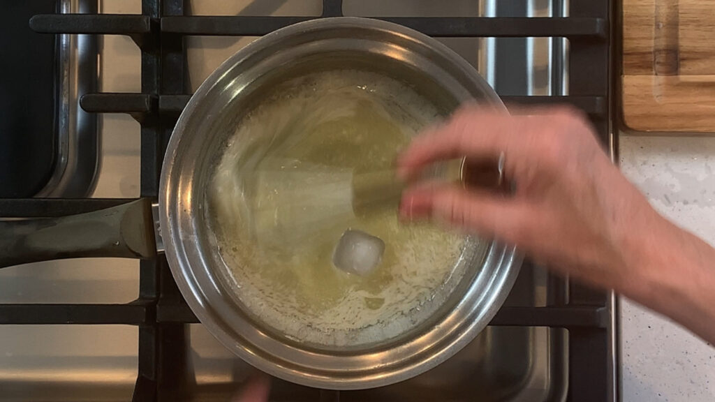 Adding an ice cube to a broken beurre blanc sauce to rescue the emulsion