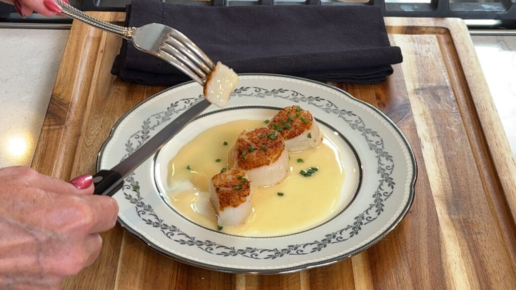 Forkful of seared scallop showing a barely translucent center