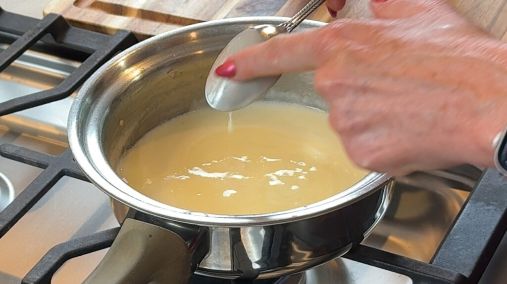 Beurre blanc sauce coating the back of a spoon to test for correct consistency