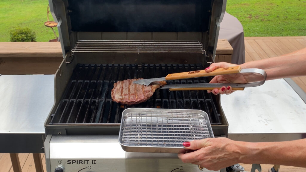 Grilled flank steak being taken off the grill.