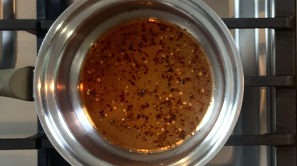 Red wine vinegar, red pepper flakes, salt, and pepper, base warming in a saucepan over low heat
