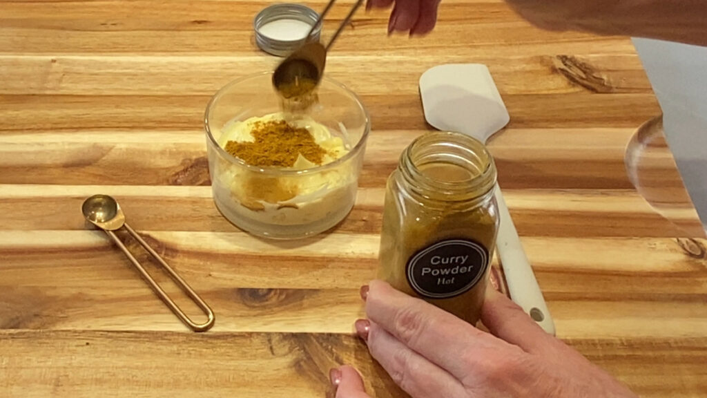 Curry powder being added to a fresh batch of homemade mayonnaise. 