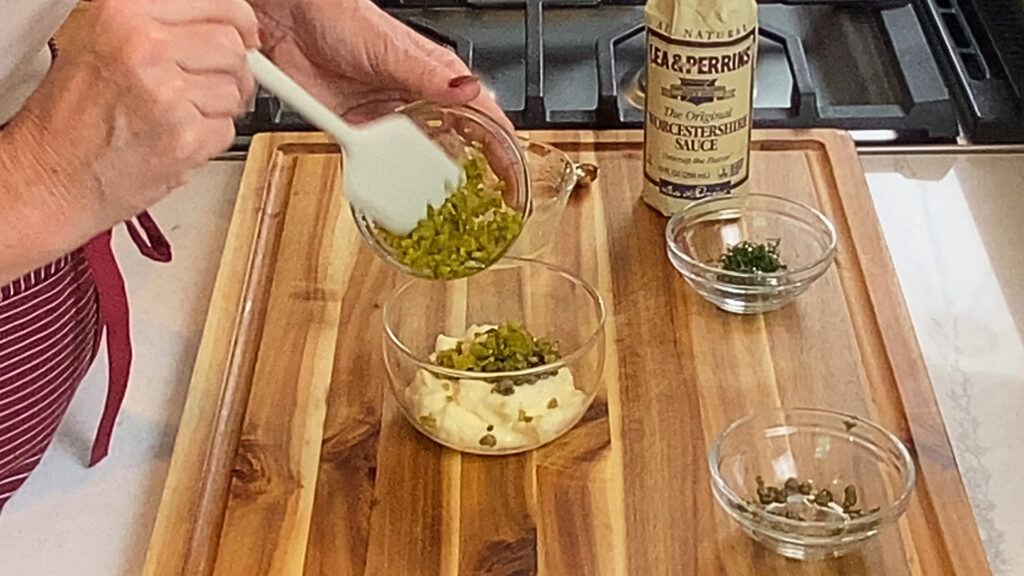 Capers and cornichons being folded into the mayonnaise